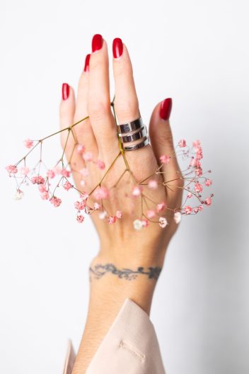 soft gentle photo woman hand with big ring red manicure hold cute little pink dried flowers white scaled e1739967568565